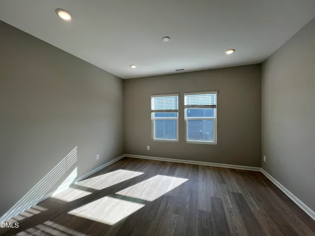 a view of an empty room with wooden floor and window