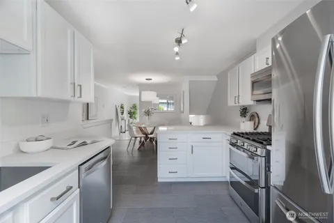 a kitchen with a sink white cabinets and stainless steel appliances