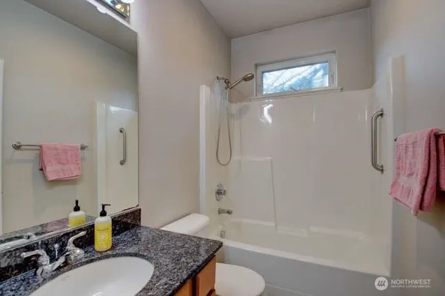 a bathroom with a granite countertop sink a toilet and shower