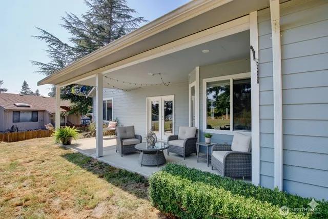 a view of a patio with couches chairs potted plants and floor to ceiling window