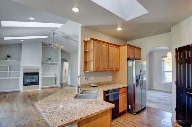 a kitchen with stainless steel appliances granite countertop a refrigerator a stove and a wooden floors