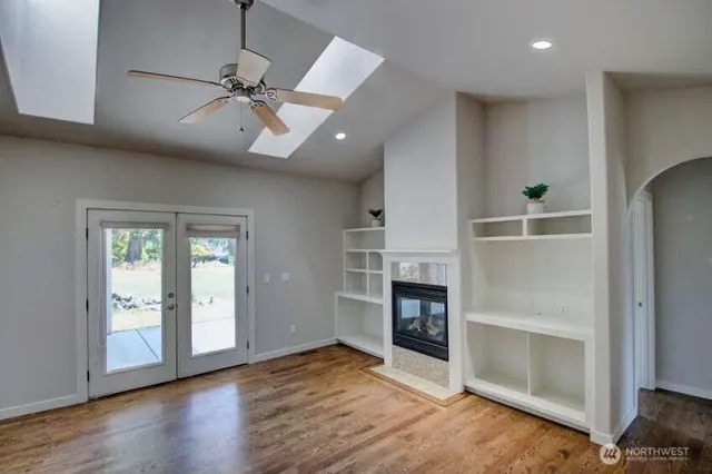 an empty room with wooden floor fireplace and windows