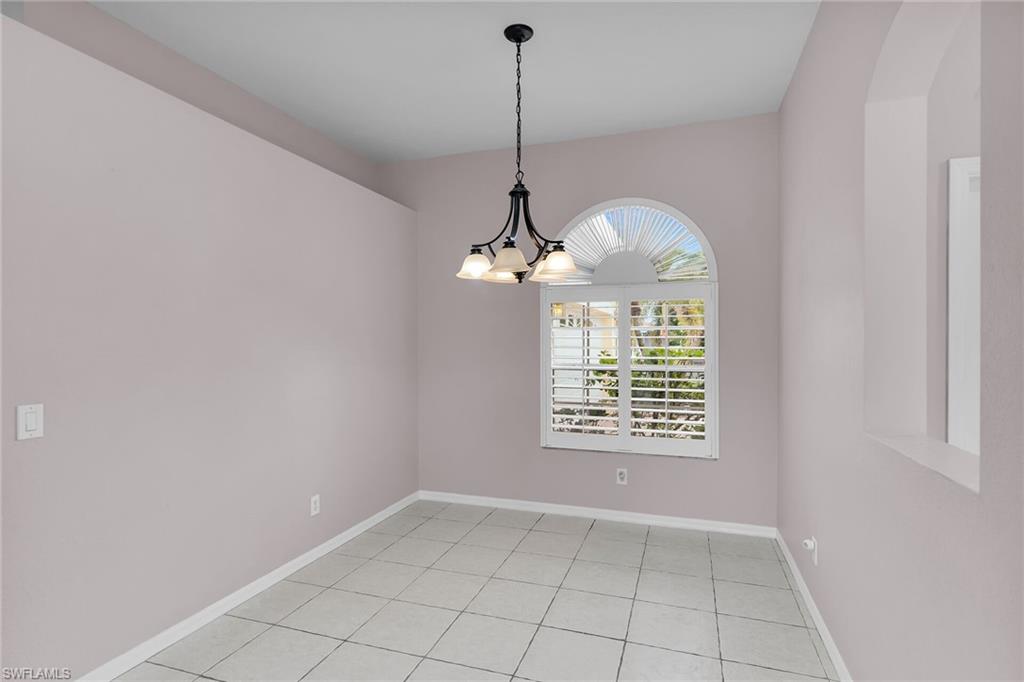 2880 Orange Grove Trail Naples, FL 34120 - Photo 6 of 42 Empty room featuring light tile patterned floors and a chandelier