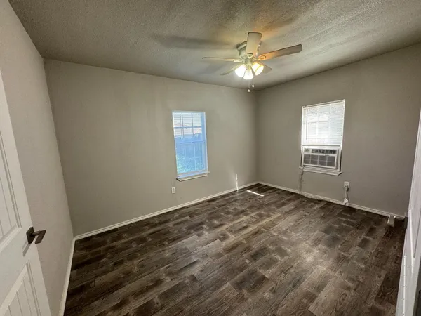 a view of an empty room and window and chandelier fan