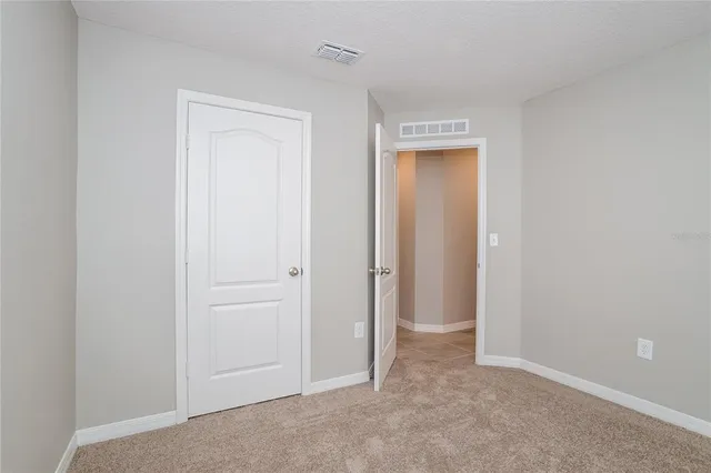 a view of an empty room with closet and a window