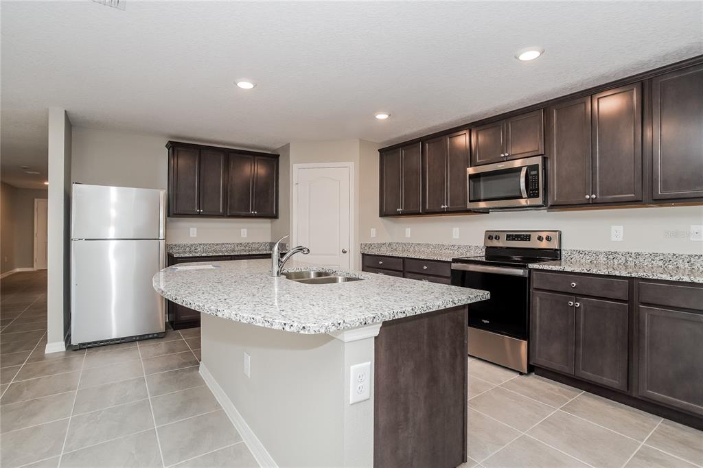 349 Daffodil Lane Kissimmee, FL 34759 - Photo 4 of 16 a kitchen with kitchen island granite countertop stainless steel appliances stove microwave refrigerator and sink
