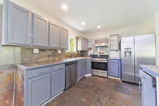 a kitchen with granite countertop a refrigerator sink and cabinets