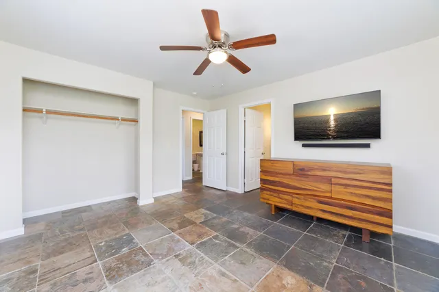 an empty room with closet and a ceiling fan