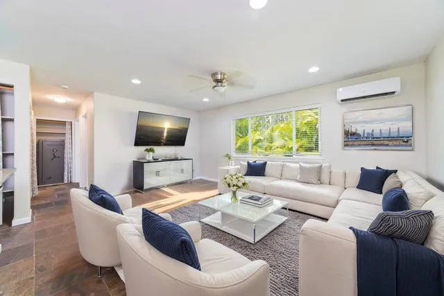 a living room with furniture a flat screen tv and a large window