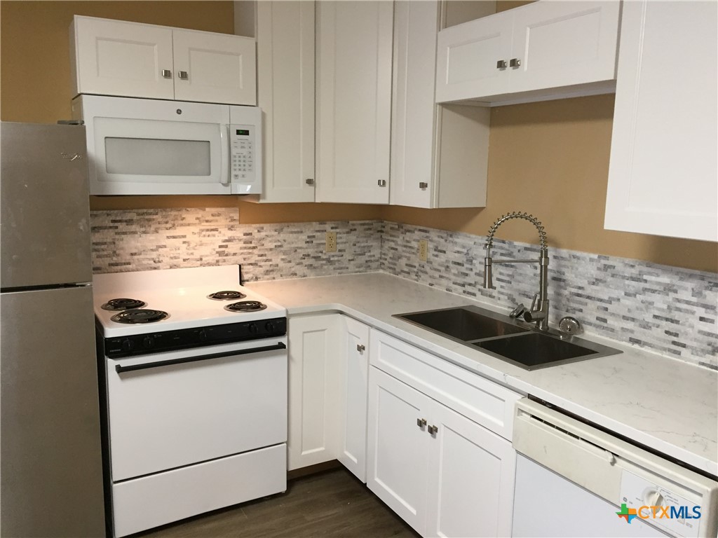 4841 Highway 35, Unit 203 Rockport, TX 78382 - Photo 20 of 23 a kitchen with white cabinets sink and white appliances