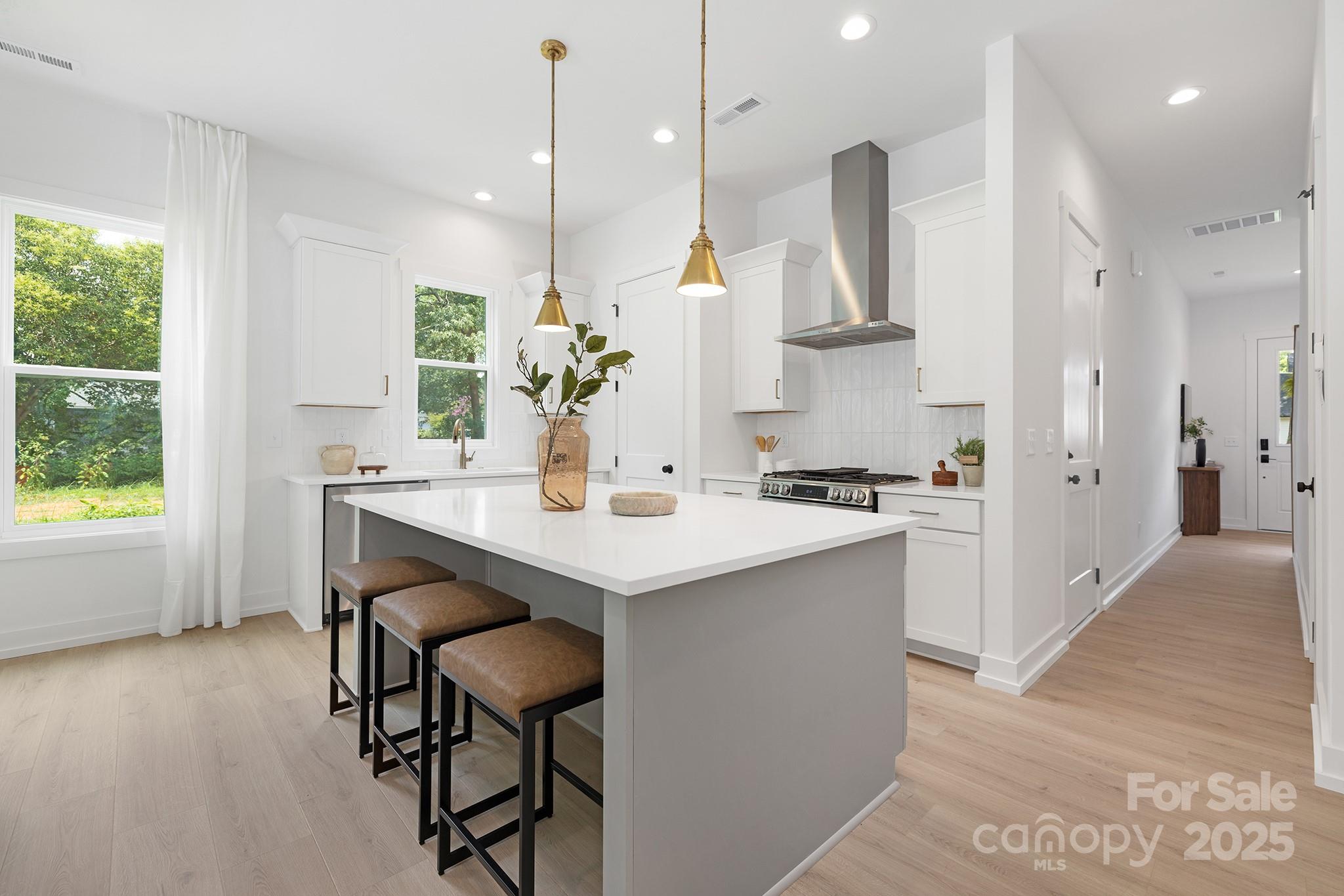 511 Bowman Road Charlotte, NC 28217 - Photo 8 of 21 a kitchen with stainless steel appliances kitchen island a table chairs in it and wooden floors