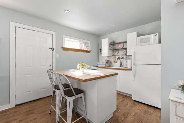 a kitchen with a refrigerator a stove a sink and a dining table with wooden floor