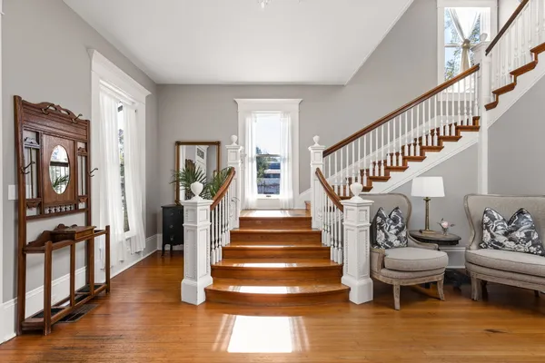 a view of staircase with lots of frames on wall and wooden floor