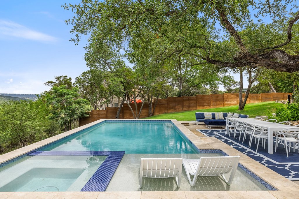 716 North Commons Ford Road Austin, TX 78733 - Photo 24 of 30 Expansive backyard featuring a rectangular swimming pool with an integrated spa, surrounded by travertine-style coping