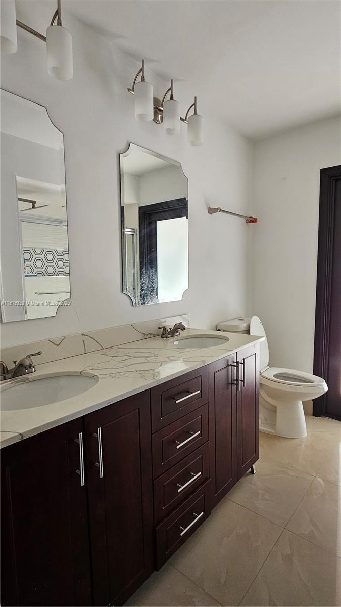 8004 Southwest 29th Street Davie, FL 33328 - Photo 16 of 39 a bathroom with a granite countertop sink a toilet and mirror