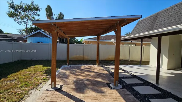 a view of a refrigerator in kitchen and an empty room with wooden floor
