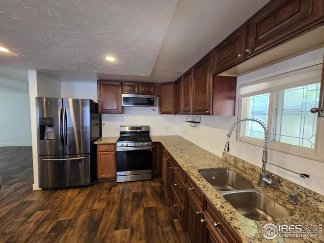 a kitchen with granite countertop a refrigerator a sink a stove and cabinets