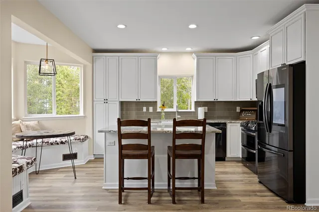 a kitchen with stainless steel appliances granite countertop a stove a refrigerator a kitchen island a stove and a refrigerator with wooden floor