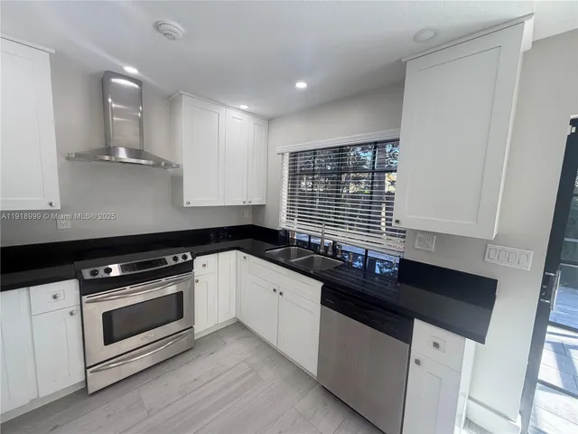 a kitchen with granite countertop white cabinets and black appliances