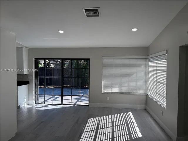 an empty room with wooden floor and fan