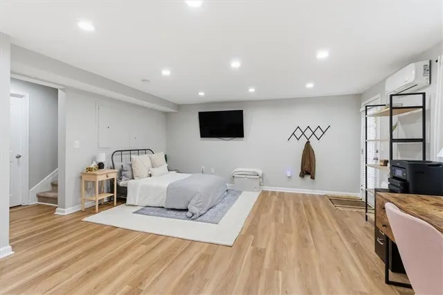 a spacious bedroom with a bed and a flat tv screen on wall