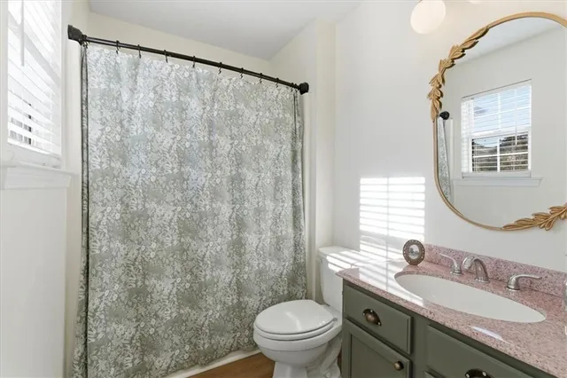 a bathroom with a granite countertop sink a toilet and a mirror