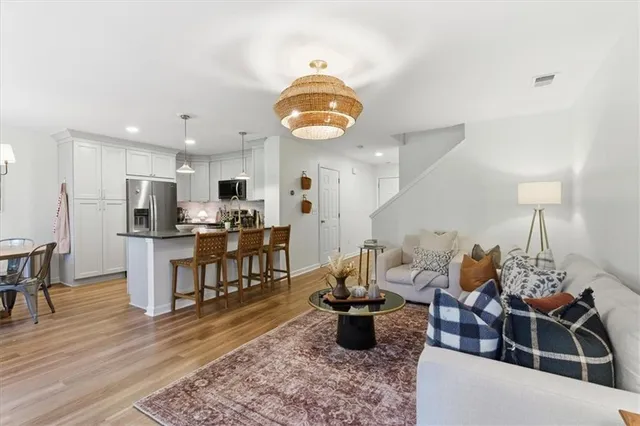 a kitchen with stainless steel appliances kitchen island granite countertop a stove a refrigerator a sink a dining table and chairs with wooden floor