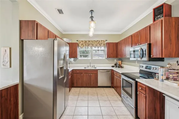 a kitchen with stainless steel appliances granite countertop a refrigerator a sink dishwasher a stove with wooden cabinets and floor