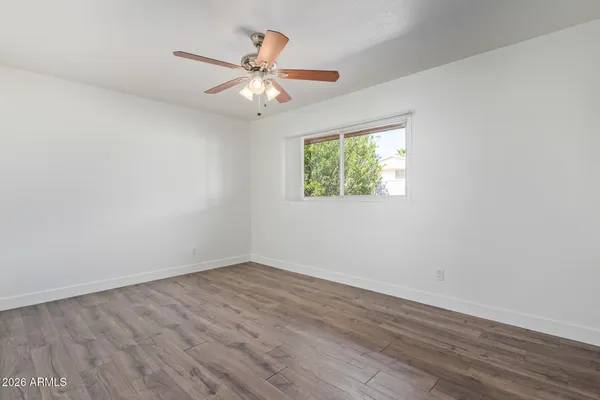 an empty room with wooden floor fan and windows