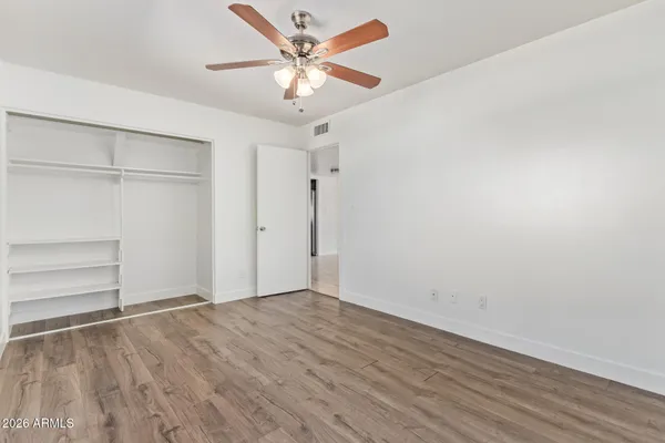 an empty room with a ceiling fan and wooden floor