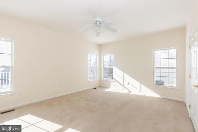an empty room with windows and ceiling fan