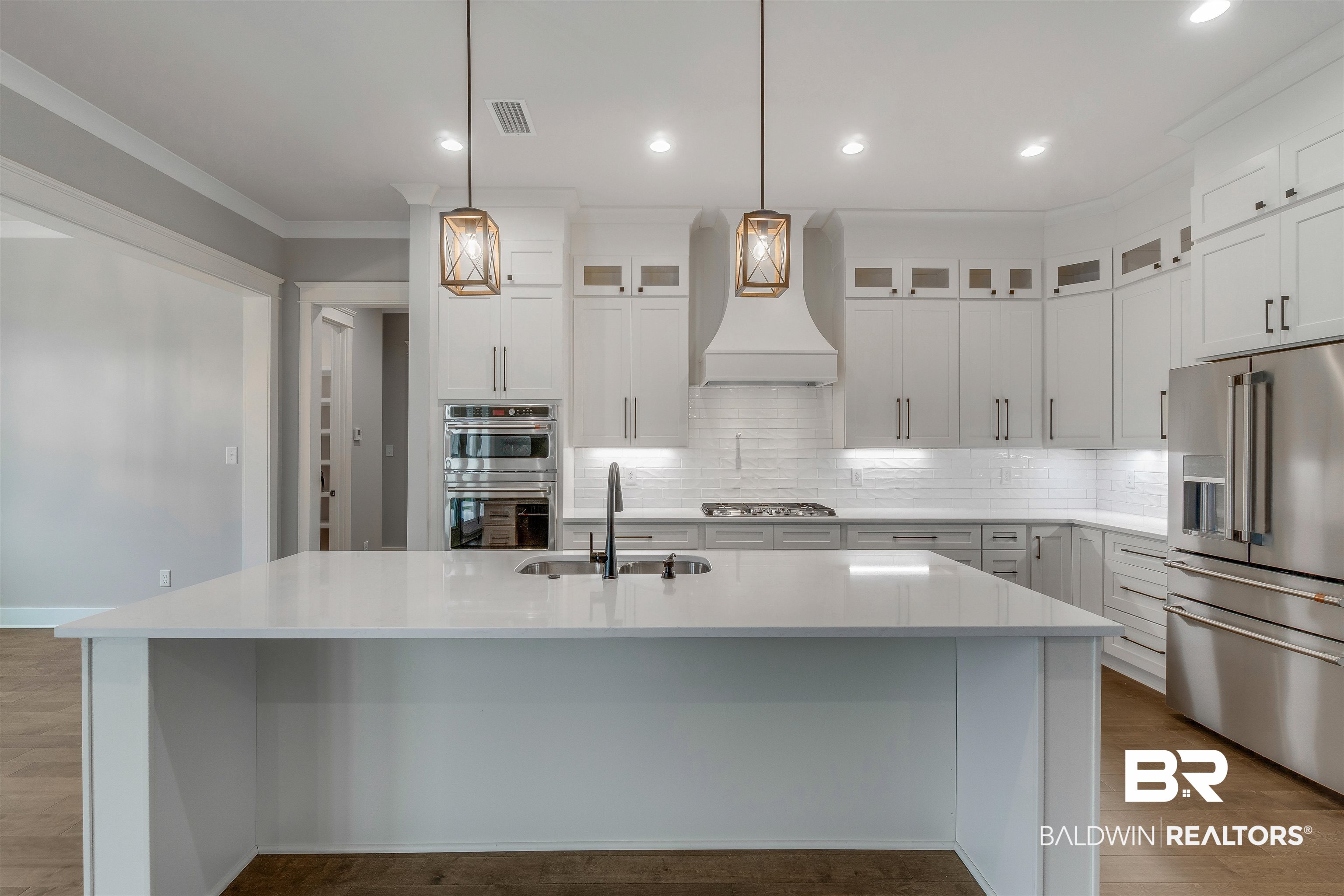 10985 Atrium Avenue Fairhope, AL 36532 - Photo 6 of 58 Kitchen with stainless steel appliances, white cabinets, tasteful backsplash, a spacious island, and ornamental molding