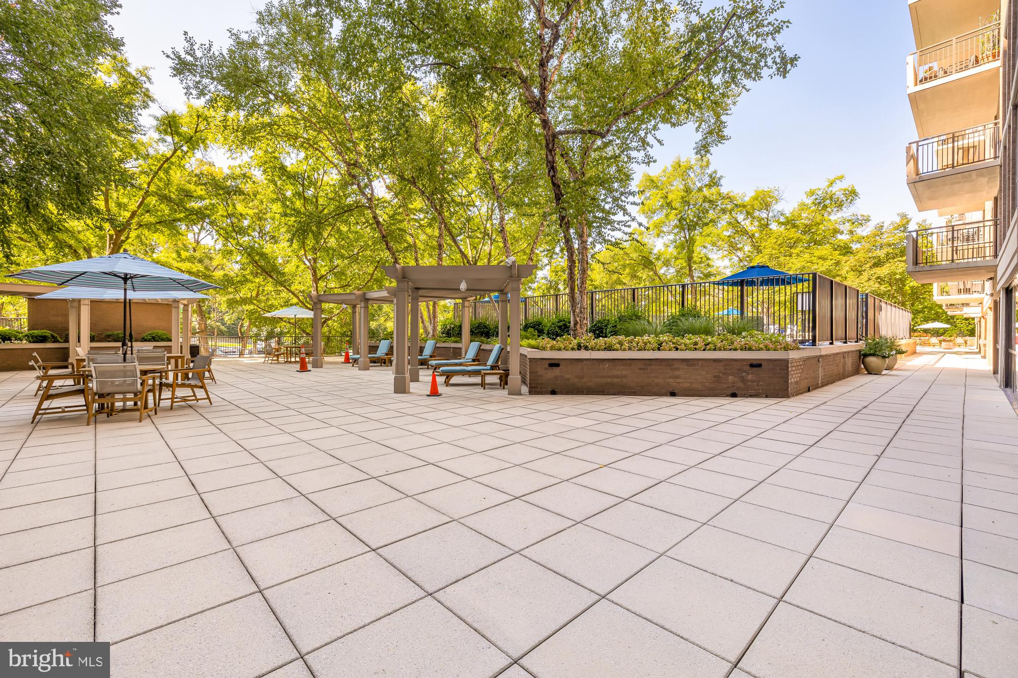 4620 North Park Avenue, Unit 1211E Chevy Chase, MD 20815 - Photo 30 of 37 a view of patio with table and chairs under an umbrella with large trees
