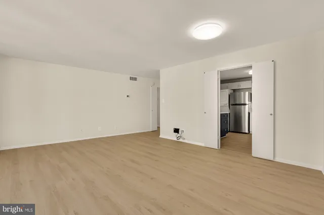 a view of an empty room with wooden floor and closet
