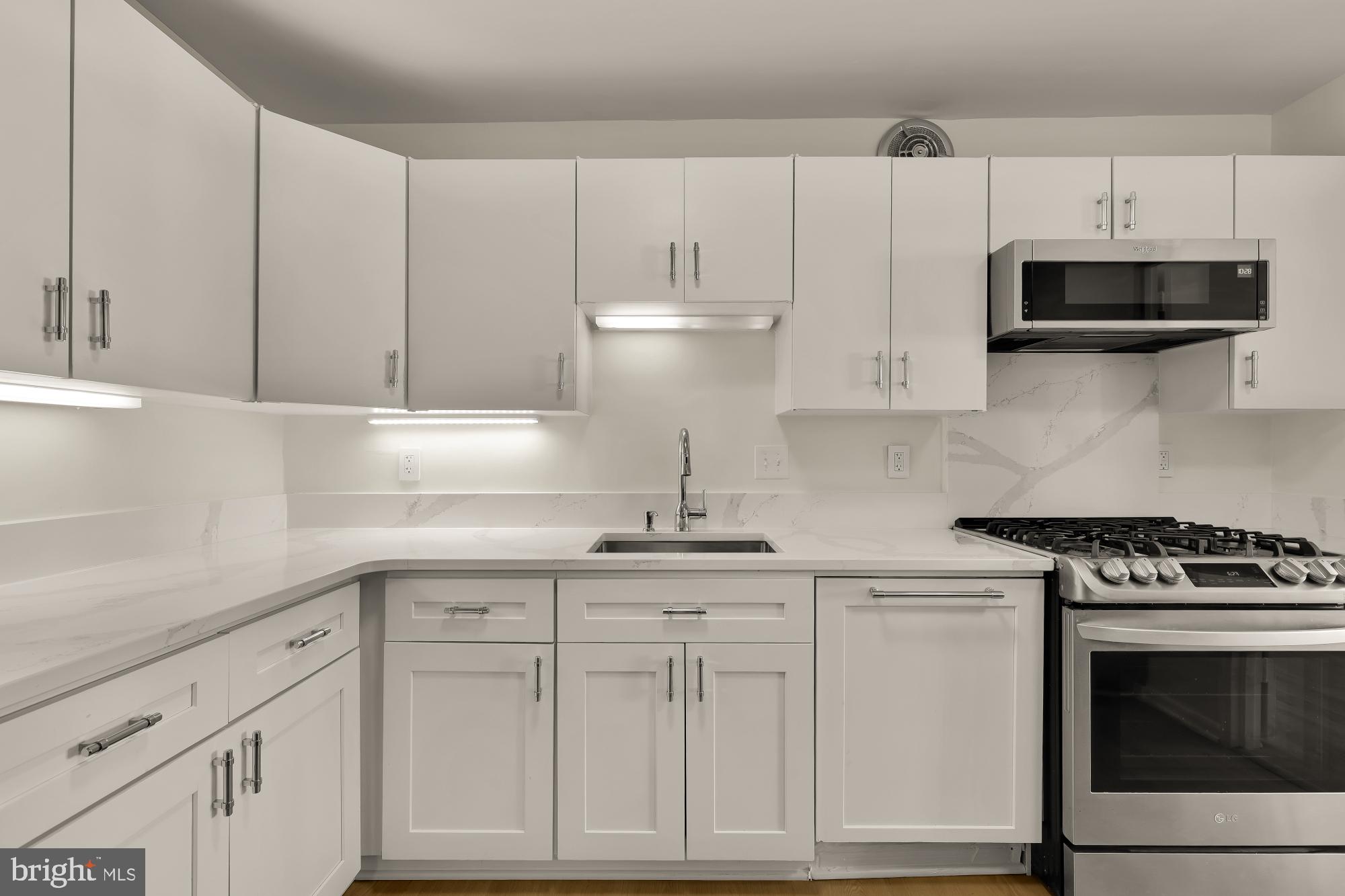 4620 North Park Avenue, Unit 1211E Chevy Chase, MD 20815 - Photo 9 of 37 a kitchen with white cabinets and white appliances
