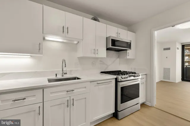 a kitchen with white cabinets and stainless steel appliances
