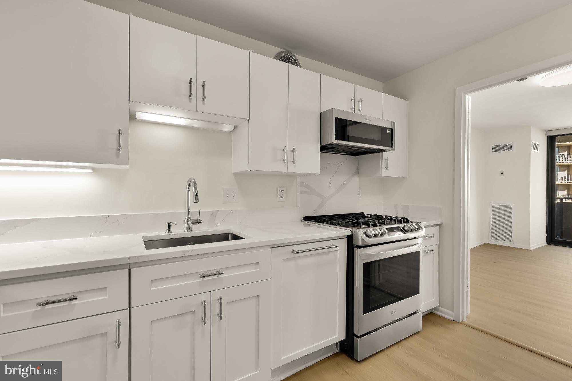 4620 North Park Avenue, Unit 1211E Chevy Chase, MD 20815 - Photo 10 of 37 a kitchen with white cabinets and stainless steel appliances