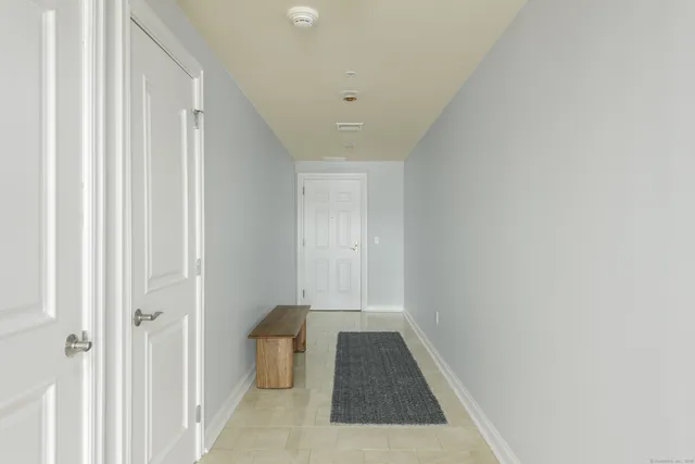 a view of a hallway with white walls and a window
