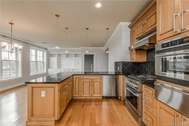 a kitchen with stainless steel appliances granite countertop hardwood floor sink stove and granite counter top