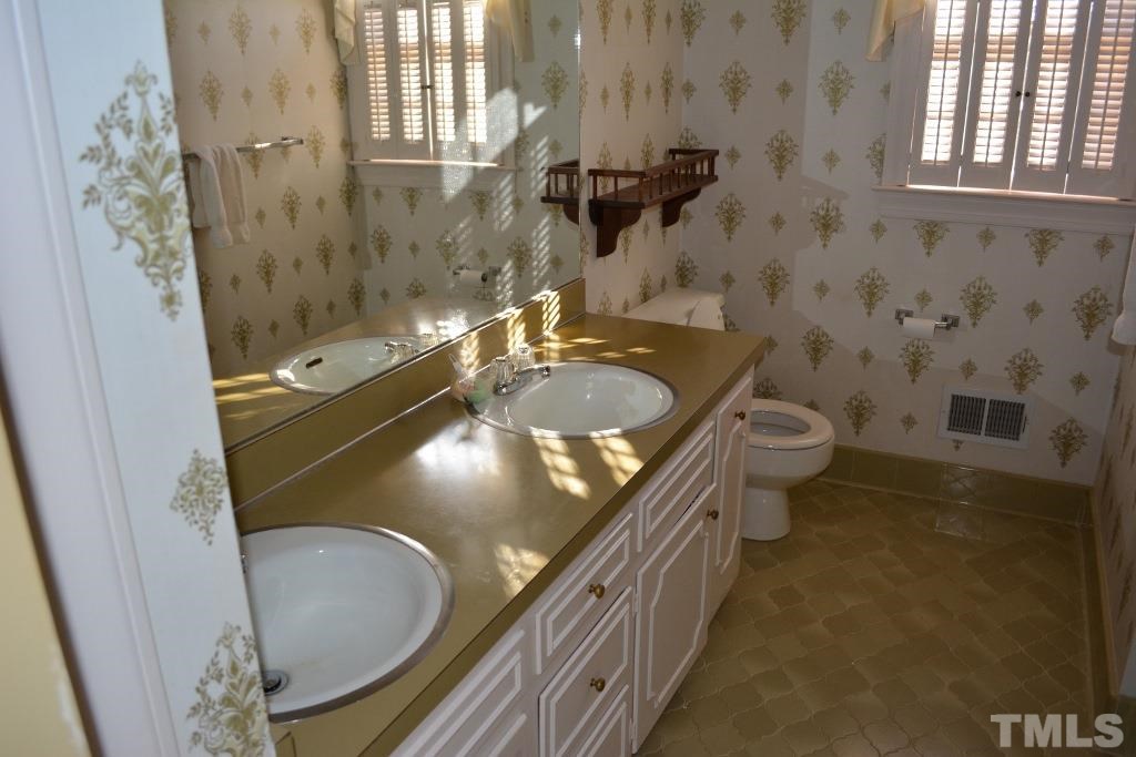 2808 Glen Burnie Drive Raleigh, NC 27607 - Photo 15 of 23 a bathroom with a granite countertop sink a toilet a mirror and shower