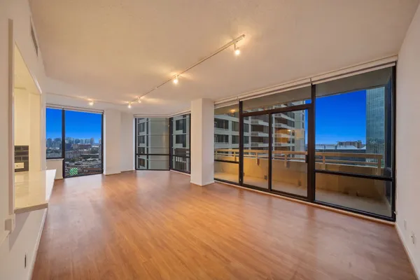a view of an empty room with window and wooden floor