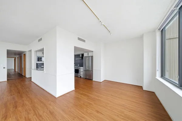 a view of an empty room with wooden floor and a window