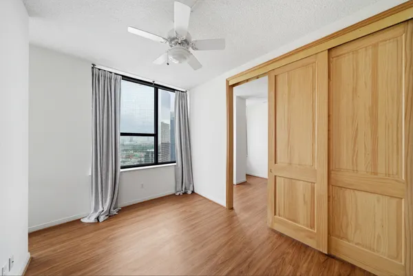 an empty room with wooden floor staircase and windows