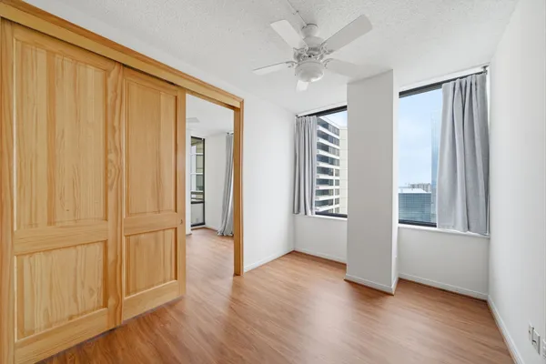 a view of an empty room with a window and wooden floor