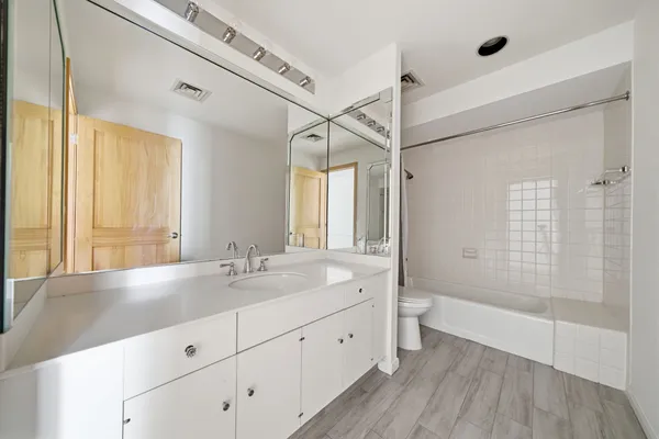 a spacious bathroom with a double vanity sink a toilet and a large mirror