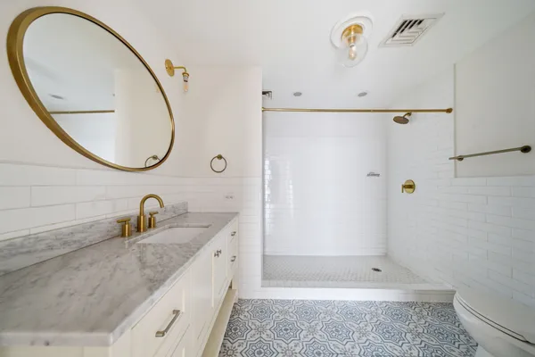 a bathroom with a granite countertop sink a toilet and a mirror