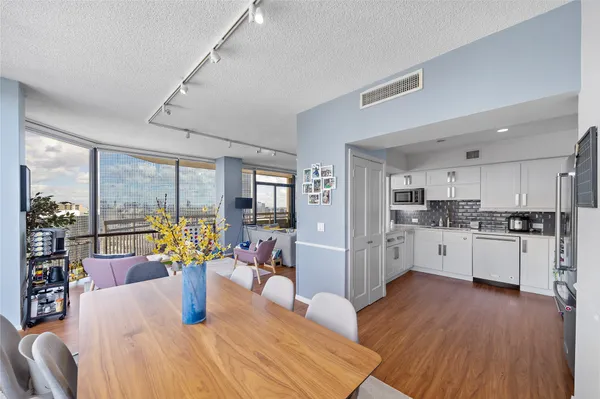 a kitchen with stainless steel appliances granite countertop a refrigerator a stove top oven and a dining table with wooden floor