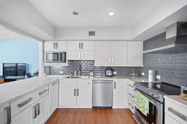 a kitchen with stainless steel appliances white cabinets sink and wooden floor
