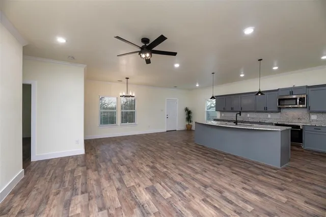 a kitchen with stainless steel appliances granite countertop a sink a stove and a wooden floors