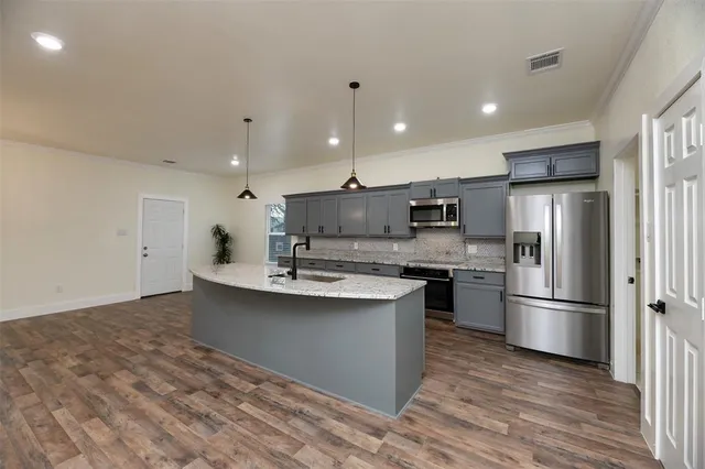 a open kitchen with kitchen island a sink stainless steel appliances and cabinets